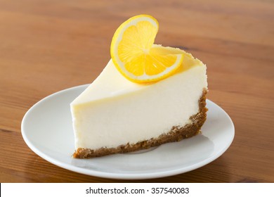 Slice of Lemon Cheesecake on white plate on wooden background