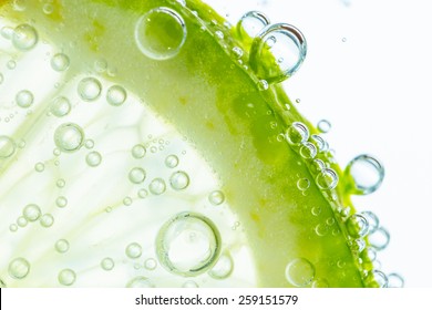 Slice of lime in water with bubbles