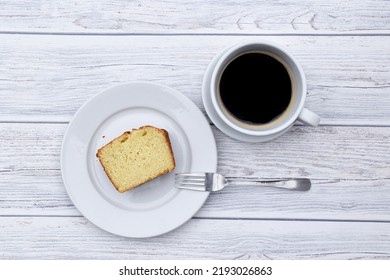 A Slice Of Loaf Cake On A Plate With A Fork And A Cup Of Black Coffee Next To It From Above