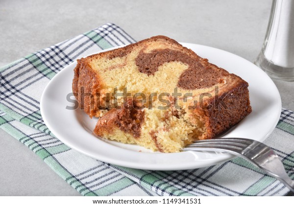 A\
slice of marble cake with a missing bite on a plate\
