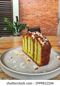 A Slice Of Pandan Green Soft Pound Cake With Coconut Shred On A Grey Flat Plate