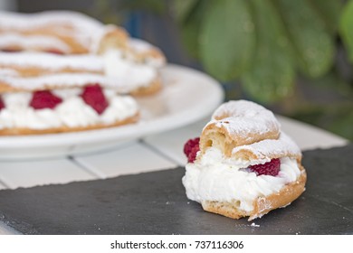 A slice of Paris Brest cake. Background: the cake and some leaves.