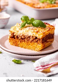 Slice Of Pastitsio, Traditional Greek Dish Like Lasagna Casserole With Bucatini Pasta, Béchamel Sauce With Parmesan And Fresh Basil Leaf, Served On A Plate 