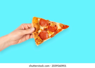 Slice Of Pepperoni Pizza In Hand Isolated On Blue. Top View On Paperoni Pizza. Concept For Italian Food, Street Food, Fast Food, Quick Bite