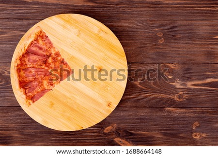 A slice of pizza bacon, on bamboo bottom, on wooden table, top view, space for text