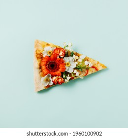 Slice of pizza with various spring flowers on a pastel turquoise background. Creative food or natural concept. Flat lay, top view.