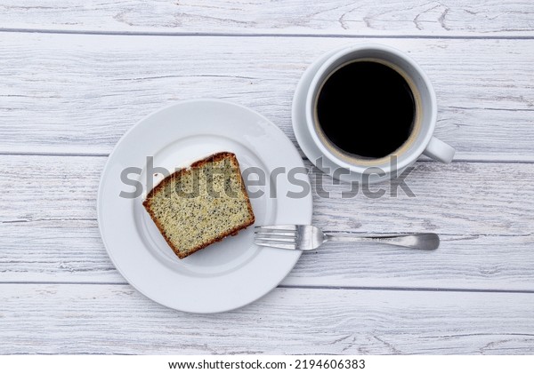 a slice of poppy seed loaf cake and a cup of black\
coffee 