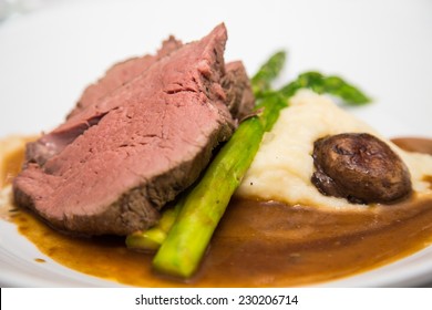 Slice Of Prime Rib On Asparagus With Gravy, Mushroom And Mashed Potatoes