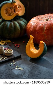 Slice of pumpkin among large pumpkins on a dark background - Shutterstock ID 1189535239