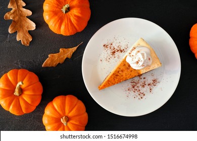 Slice Of Pumpkin Cheesecake With Whipped Cream, Overhead Table Scene With A Black Stone Background