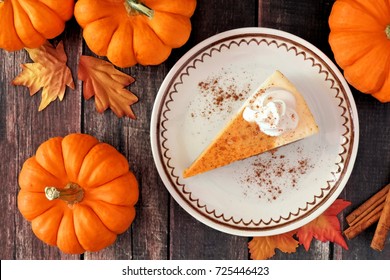 Slice Of Pumpkin Cheesecake With Whipped Cream, Overhead Table Scene On A Rustic Wood Background