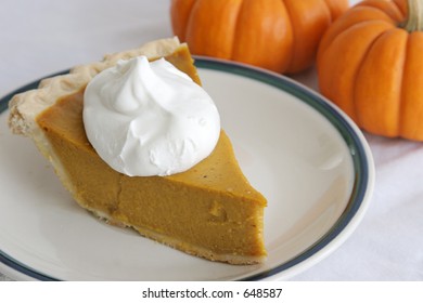 A Slice Of Pumpkin Pie Garnished With Whipped Cream.