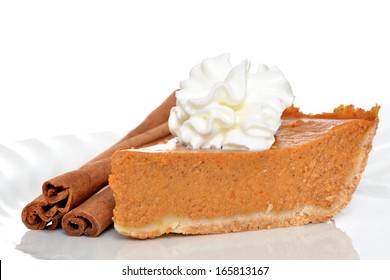 slice of pumpkin pie with whipped topping and cinnamon sticks isolated on white background