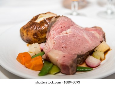 Slice Of Rare Prime Rib And Baked Potato On A Plate With Fresh Vegetables