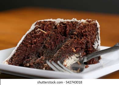 A Slice Of Rich Moist Chocolate Cake On A White Plate With Layers