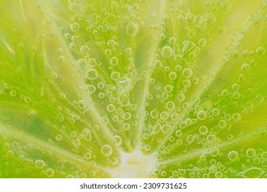 Slice of ripe lime in water. Close-up of lime in liquid with bubbles. Slice of ripe lime in sparkling water. Macro horizontal image of fruit in carbonated water. Detail of lime slice with bubbles. - Powered by Shutterstock