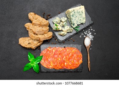 Slice of Roquefort cheese and chorizo sausage on stone serving board
