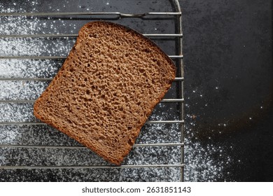 Slice of rye bread on black tray background with flour, top view