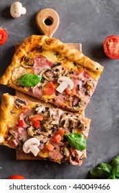 A Slice Of Square Pizza With Basil Tomatoes And Mushrooms On A Wooden Board.