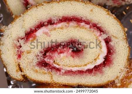 A slice of swiss roll sponge cake with jam and cream in close up