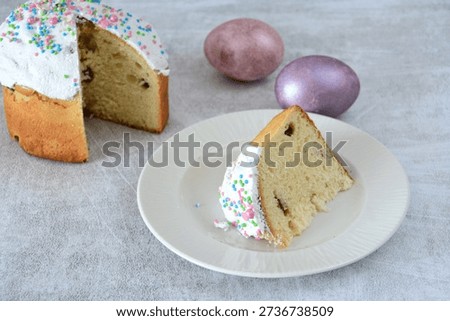 a slice of Traditional Easter Kulich with Icing, Sprinkles on a plate and Eggs copy space