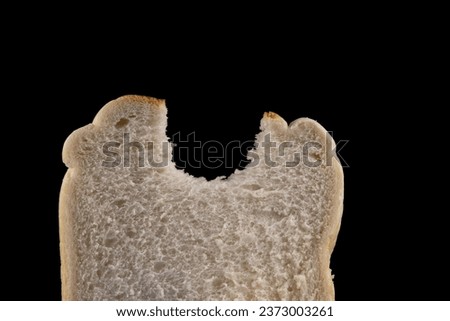 Slice of white bread with bite taken out isolated on a black background