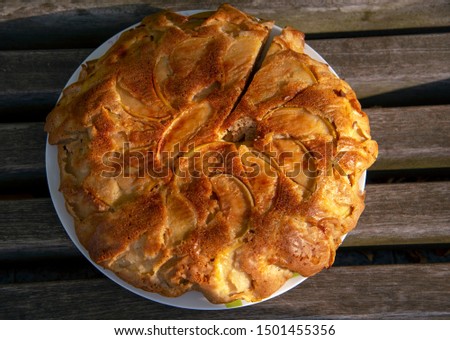 A sliced Apple pie sits on a plate on the wooden countertop.