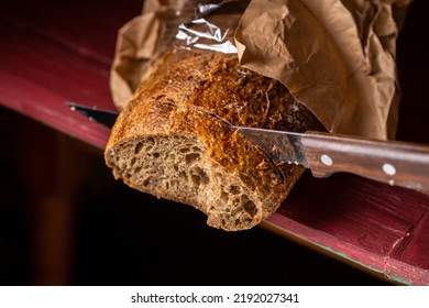 Sliced baguette with a bread knife. Bread made from buckwheat flour. Useful bread. Dark background. Banner. Place for text. - Shutterstock ID 2192027341