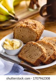 Sliced Banana Nut Loaf Cake And Butter On A Plate With A Bunch Of Bananas In Background