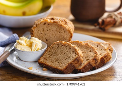 Sliced Banana Nut Loaf Cake And Butter On A Plate With A Bunch Of Bananas In Background