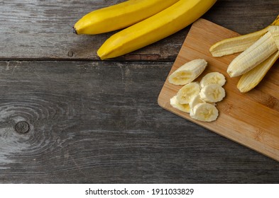 Sliced banana on a wood cutting board on a rustic wood background preparing for cooking. - Powered by Shutterstock