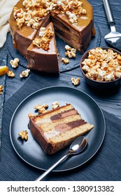 Sliced Banana Sponge Cake Layered With Peanut Butter Mousse And Topped With Chocolate Ganache, Melted Caramel And Sweet Popcorn, Vertical View From Above