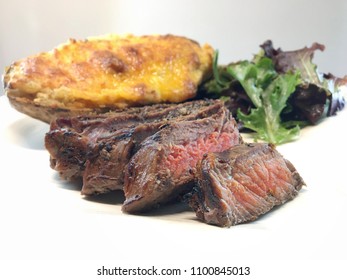 Sliced Beef Steak And Twice Baked Potato With Mixed Greens Salad.