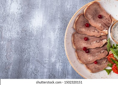 Sliced beef tongue with cranberry, salad and sauce. Top view. Copy space