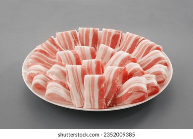 Sliced belly pork for shabu or Japanese hot pot in white plate  on grey background.