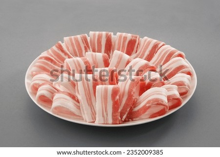 Sliced belly pork for shabu or Japanese hot pot in white plate  on grey background.