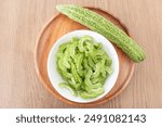 Sliced Bitter gourd, or bitter melon. it called pare in Indonesia. On a wooden tray. Ready to cook. Perfect for recipe or any commercial purpose