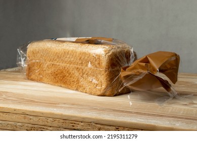 Sliced Bread In Plastic Bag On Wooden Table. Toast Bread Slices Package, Breakfast Grain Loaf Cuts In Plastic Wrap