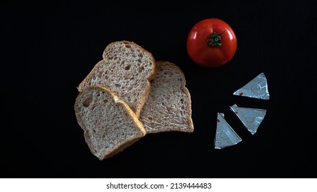Sliced bread and red tomato with triangle cheese, lay down on table, consept food, bread slices with tomato isolated on black background, top view