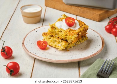 Нарезанная ​​капуста, морковь и яйцо запеканка на тарелке на светлом деревянном фоне. Подается со сметаной и свежими помидорами черри. 
