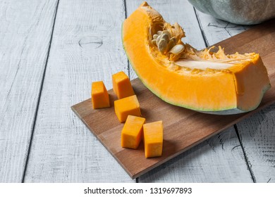 Sliced and chopped pumpkin pieces. Pumpkin with seeds. Pumpkin chunks on wooden background. Fresh and ripe pumpkin detail vegetable and halloween composition
