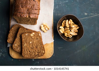 Sliced dark homemade bread with walnuts on a dark background. Top View - Shutterstock ID 1014145741