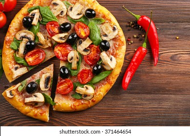 Sliced delicious tasty pizza with vegetables on wooden table - Powered by Shutterstock