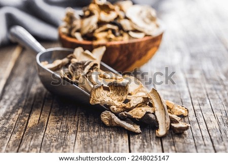 Sliced dried mushrooms in scoop on the wooden table.