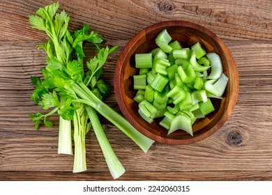 Sliced fresh celery on wooden plate on wooden background - Shutterstock ID 2242060315