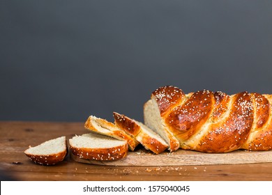 Sliced fresh challah bread on the wood table.
