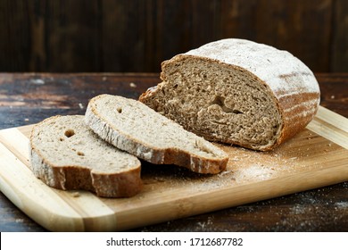 sliced fresh rye bread on a brown wooden background. simple rustic background