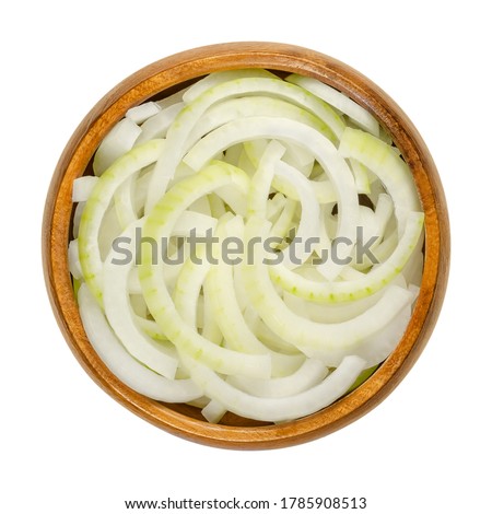 Sliced fresh white onions in wooden bowl. Onions cut into rings. A cultivar of dry onion,  Allium cepa, with white skin and flesh. Closeup, from above, on white background, isolated, macro food photo.