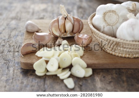 sliced garlic, garlic clove, garlic  bulb in wicker basket place on chopping block on vintage wooden background