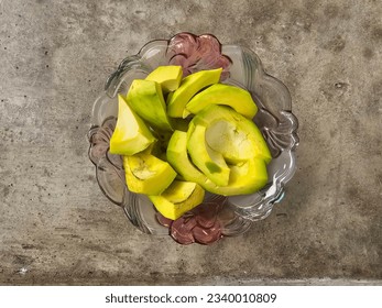 Sliced ​​avocado in glass bowl on cement table from top view - Powered by Shutterstock